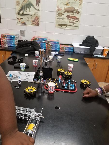 Two students using hand tools to assemble robot.